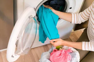 mulher tirando roupa da máquina de lavar