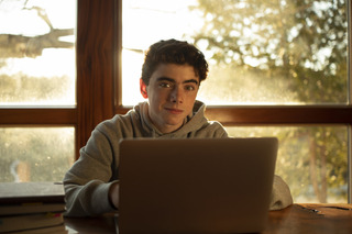 Un hombre joven usa su portátil para realizar las tareas de la universidad