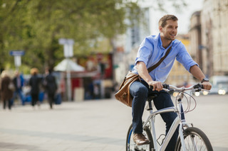 Homem vestindo azul passeia com bicicleta na rua