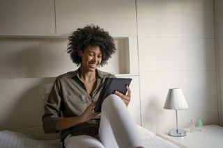 Mulher sorri enquanto olha para um tablet