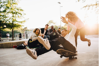 Grupo de amigos divirtiéndose junto a un skate