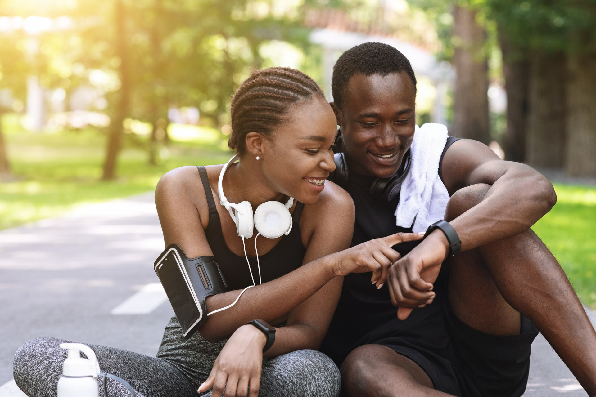 Una pareja checa los datos de un smartwatch después de hacer ejercicio.