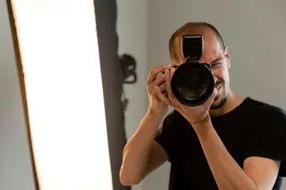 Homem tirando uma foto com flash Canon.