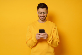 Joven y contento hombre utiliza su celular