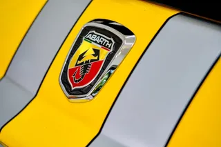 Logo de Abarth sobre automóvil amarillo y plateado.