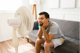 Un hombre refrescándose con un ventilador