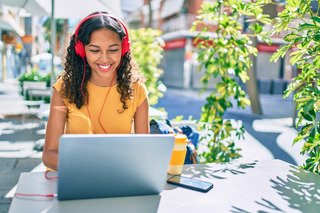 Una persona joven utiliza su notebook para trabajar mientras toma un café