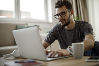 Un joven hombre trabaja en modalidad home office con su computadora Apple