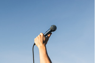 Mano hacia el cielo, sosteniendo un micrófono