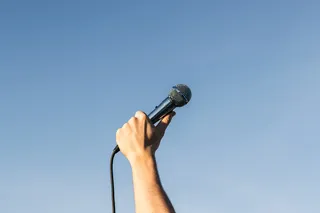 Mano hacia el cielo, sosteniendo un micrófono