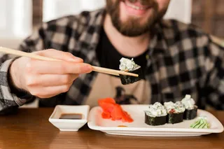 Hombre comiendo sushi con palillos
