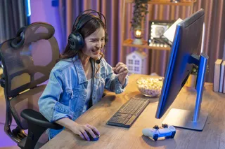 Una chica juega con su PC gamer mientras come pochoclos
