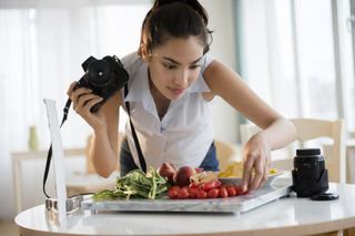 Una mujer prepara alimentos para sacarles una foto con su cámara profesional