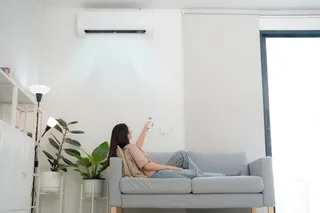 Mulher sentada sob o ar-condicionado