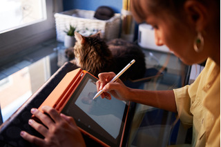 Joven junto a su gato utilizando tablet grafica