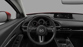 Interior de un Mazda CX-30 2025/2026 versión Touring, con vista desde el lado del conductor mostrando tablero horizontal, pantalla central integrada, volante multifunción y consola central
