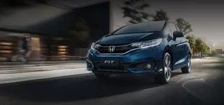Lateral de auto Honda Fit azul con fondo en movimiento.
