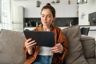 Mulher utiliza tablet Samsung em seu sofá