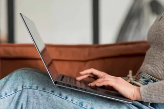 Mulher usando notebook no sofá