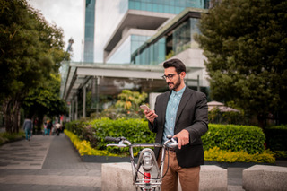 Un hombre con una bicicleta descansa en la calle mientras usa su celular Xiaomi.