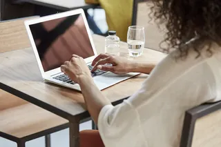 Mujer escribiendo en un Macbook en un café