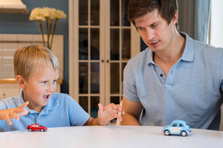 Hombre e hijo jugando con autos miniatura