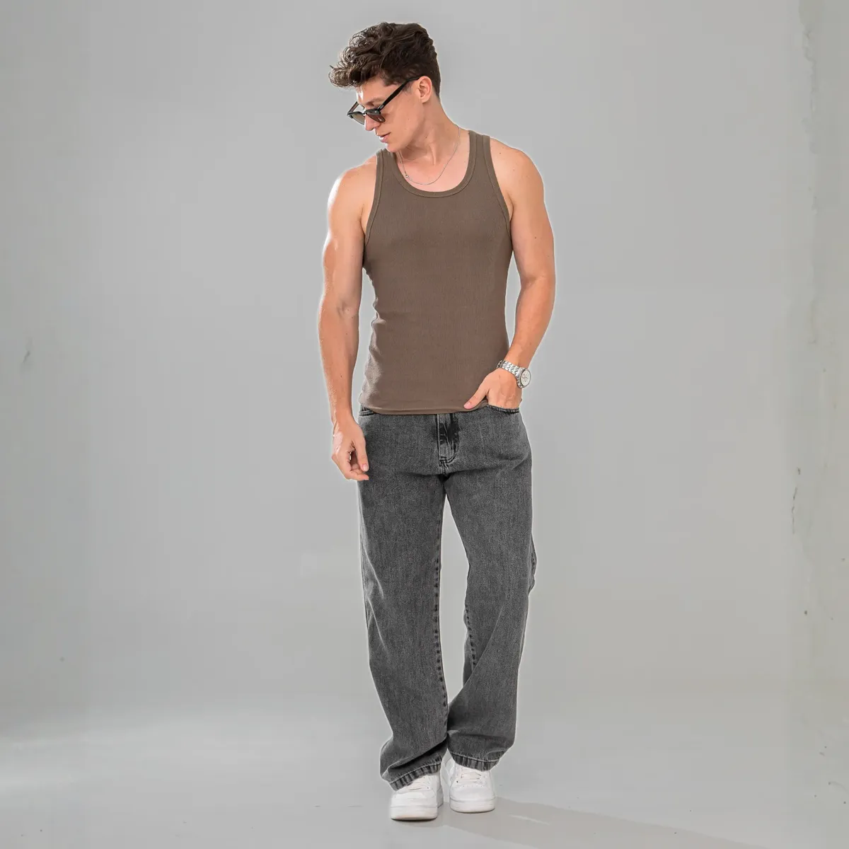 Homem de óculos escuros vestindo calça jeans balão marmorizada, vista de corpo inteiro