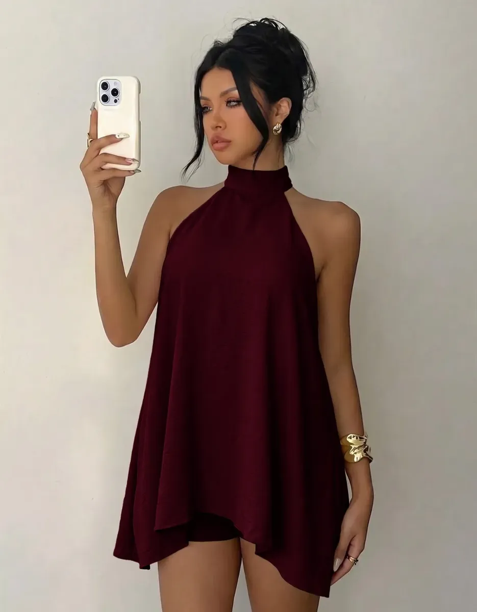 Modelo segurando celular, exibindo o conjunto vinho frente única com acessórios dourados.
