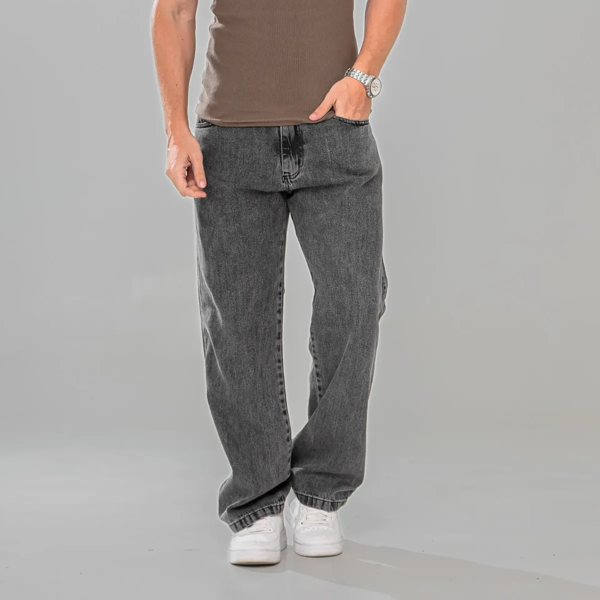 Close-up frontal de homem com calça jeans balão marmorizada e relógio de pulso
