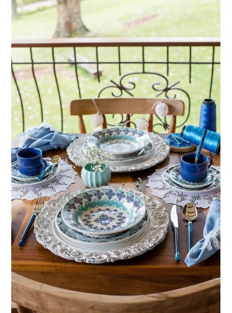 Vista aérea de uma mesa posta com o aparelho de jantar Oxford Cerâmica Lola, mostrando a disposição dos pratos, bowls, xícaras e talheres.