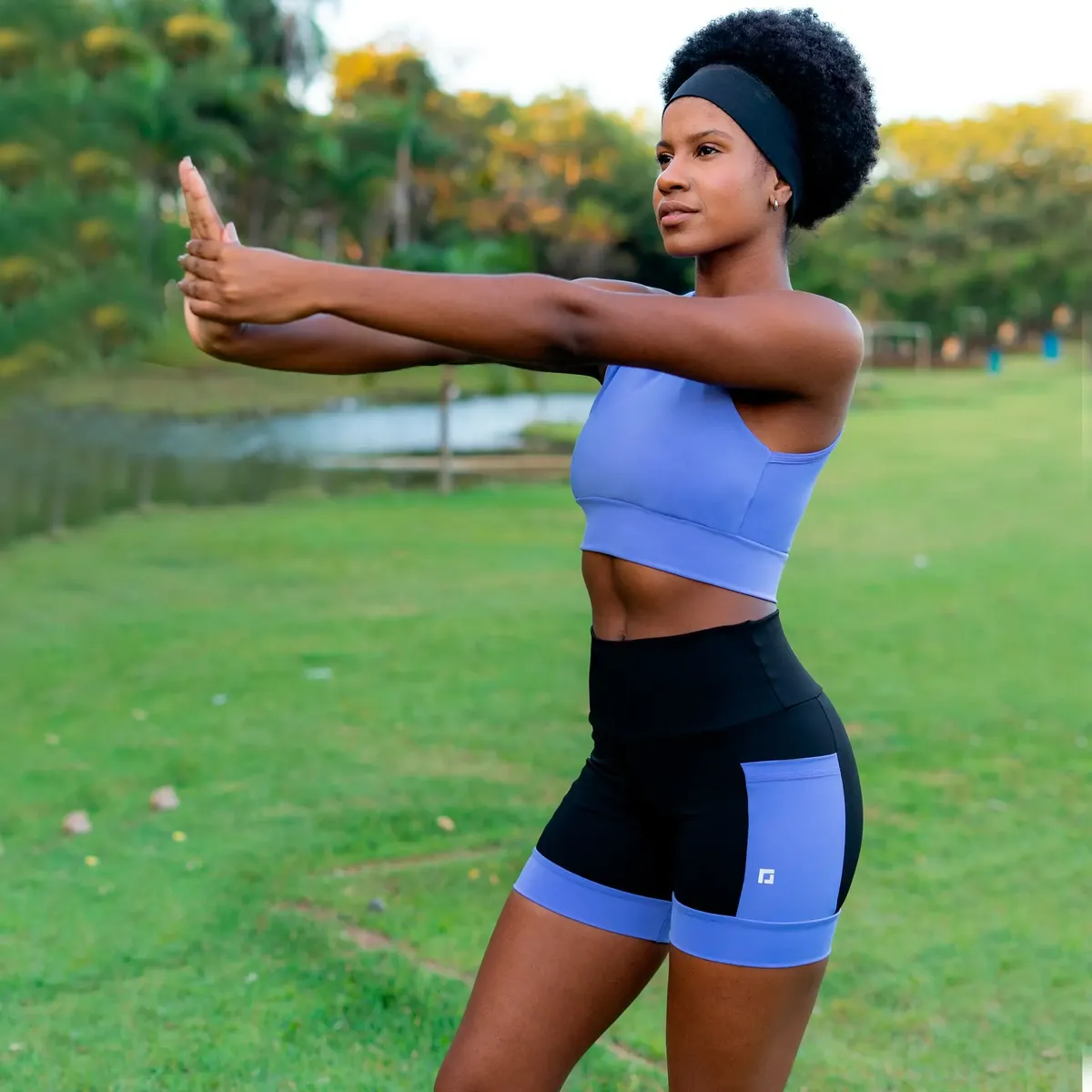 Mulher praticando exercícios ao ar livre com shorts preto e roxo de cintura alta e top combinando