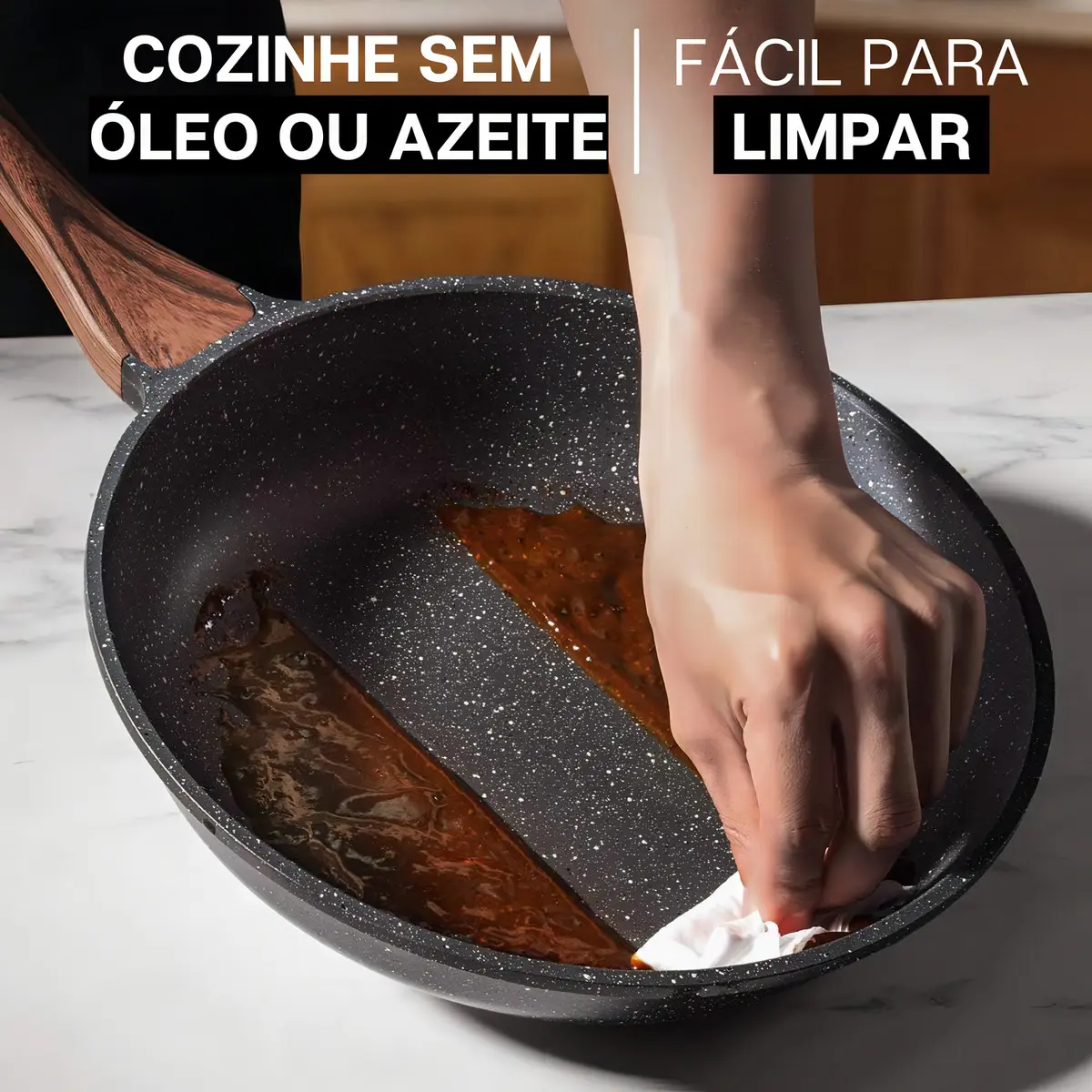 Mão limpando facilmente uma frigideira de cerâmica antiaderente suja com um papel toalha, demonstrando a facilidade de limpeza.