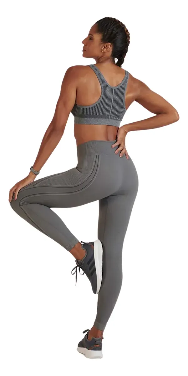 Modelo de costas em fundo branco exibindo a parte traseira da legging e top cinza