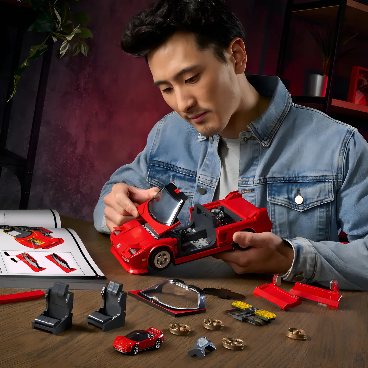 Carro montado 90 Acura NSX vermelho ao lado de rodas de reposição e peças extras