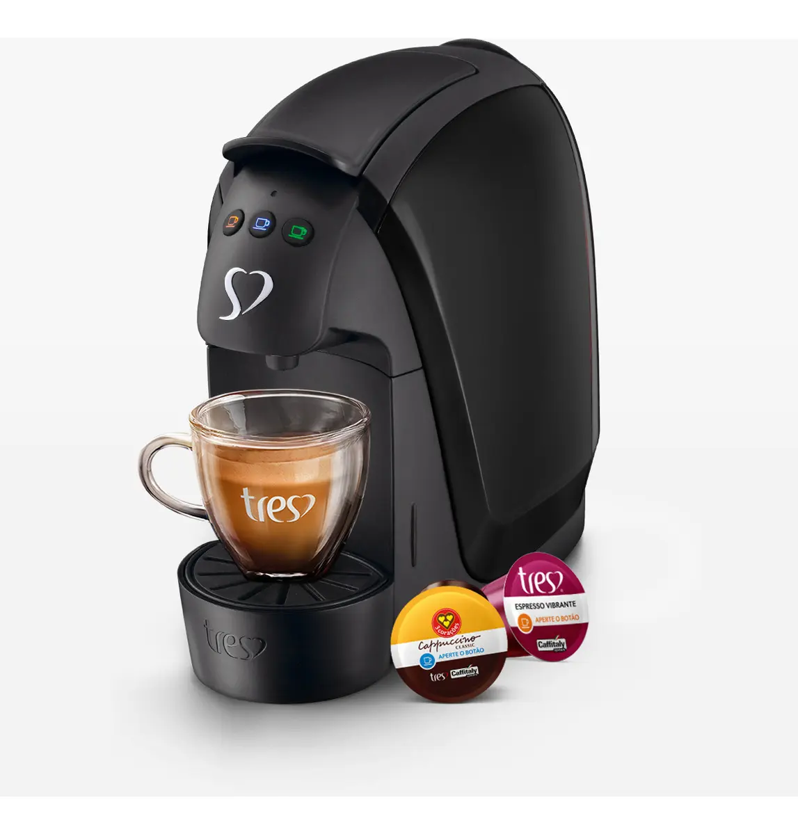 Cafeteira Espresso Três Corações Luna preta com uma xícara de café e duas cápsulas Três Corações (Cappuccino e Espresso Vibrante) ao lado.