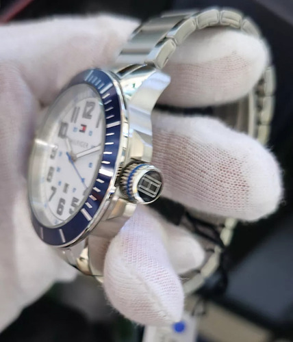 Reloj Tommy Hilfiger 1791074 con correa plateada y bisel azul sobre fondo blanco