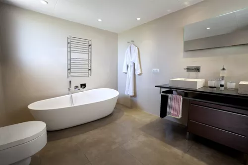 Cuarto de baño con toallero eléctrico ATRIM. Modelo con switch para ahorro  de energía.