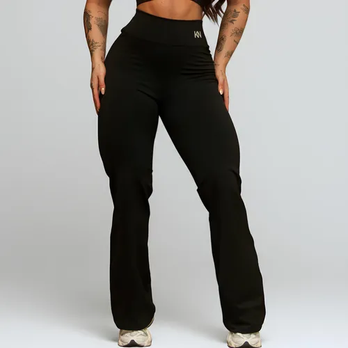 Modelo feminina usando calça legging flare preta de cintura alta com logo KN na frente