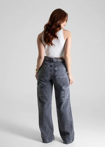 Vista traseira da modelo vestindo calça jeans wide leg Sawary preta com bolsos cargo