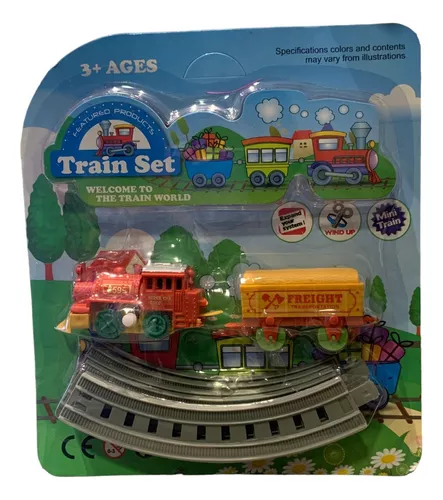 Um trem de brinquedo está nos trilhos ao lado de uma pequena casa.