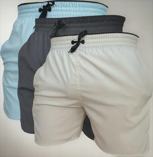Kit com três shorts masculinos de treino em cores azul claro, cinza chumbo e bege, com cordões de ajuste pretos.