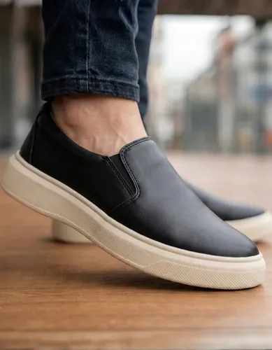 Close-up do sapatênis masculino casual slip on preto em uso, mostrando o material e a sola.