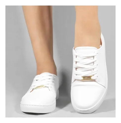 Pés de uma modelo calçando o tênis Vizzano branco com detalhe dourado na frente