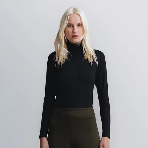 Modelo loira usando blusa preta de gola alta Insider vista de frente