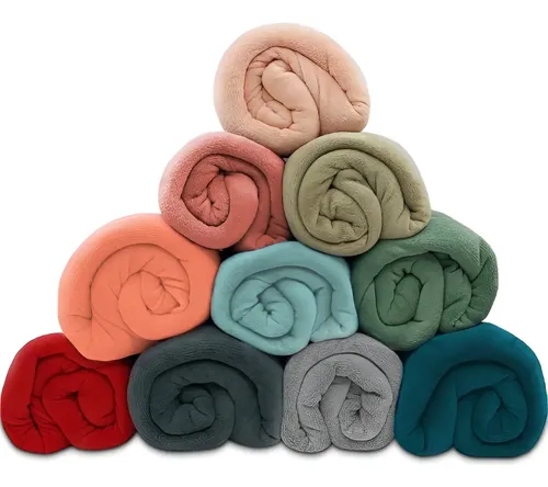 Pilha em formato de pirâmide com 11 mantas de microfibra enroladas, em diversas cores lisas vibrantes como vermelho, azul, cinza e tons pastéis, sobre fundo branco.