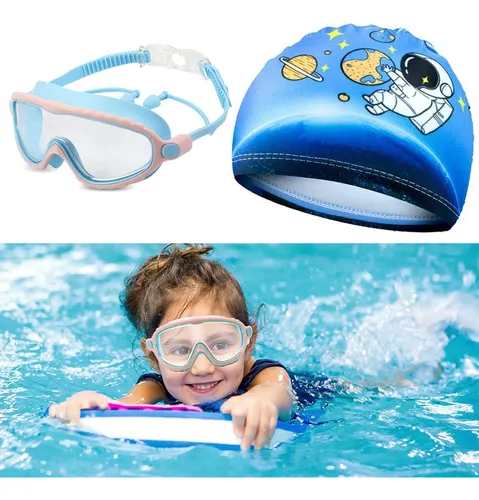 Niña pequeña con gafas impermeables y traje de baño en una clase de  natación en una piscina cubierta