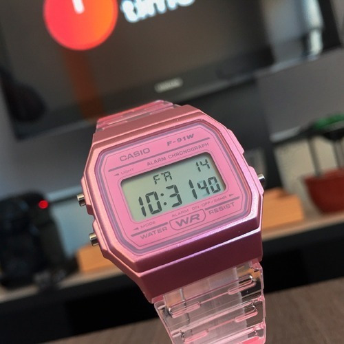 Reloj pulsera Casio Collection F-91 de cuerpo color rosa, digital, fondo gris, con correa de resina color transparente y rosa, dial negro, minutero/segundero negro, bisel color rosa y hebilla simple