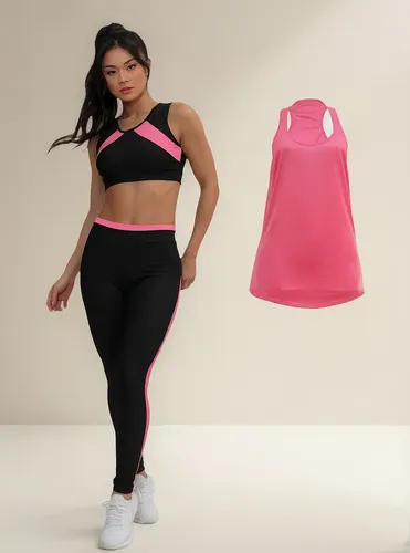 Mulher em pé vestindo conjunto fitness preto e rosa, com um top cropped e legging, ao lado de uma regata rosa solta.