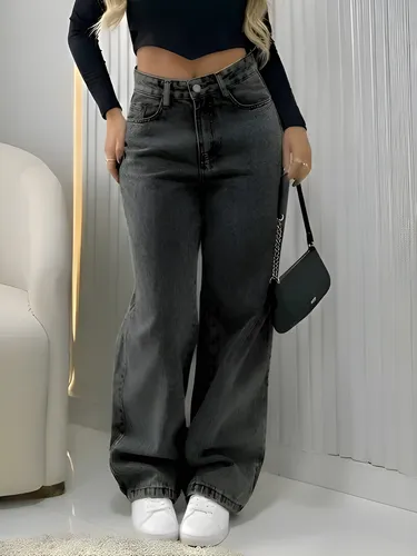 Mulher vestindo calça jeans preta wide leg com cintura alta e bolsa preta.