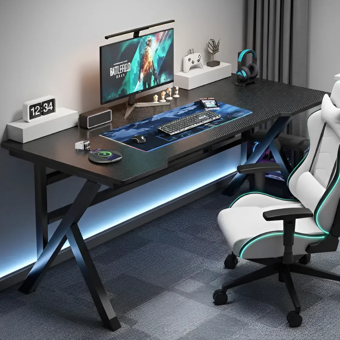 Mesa gamer preta de 120cm com estrutura em X, exibindo um setup de computador com monitor, teclado, mouse, mousepad grande, relógio digital e cadeira gamer branca ao lado.